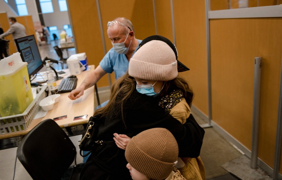 Seorang anak berusia 7 tahun, memeluk ibunya setelah menerima vaksin  Covid-19 untuk anak-anak di Montreal, Quebec pada 24 November 2021. 