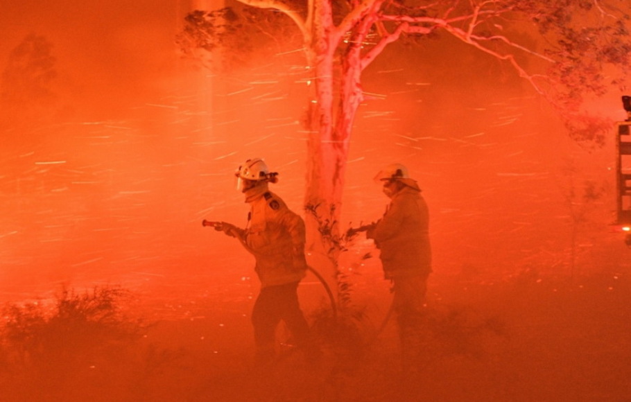 Petugas pemadam kebakaran berjuang melawan angin kencang dan bara api dalam upaya mengamankan rumah-rumah di dekatnya dari kebakaran hutan di dekat kota Nowra, negara bagian New South Wales, Australia.