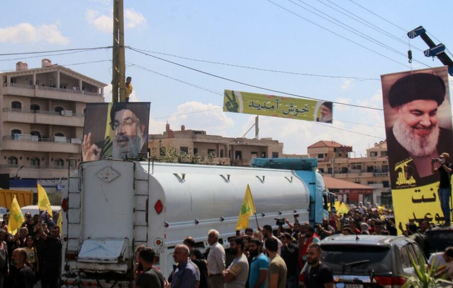 Orang-orang mengangkat potret pemimpin Hizbullah Hassan Nasrallah, ketika berkumpul untuk menyambut truk tangki yang membawa bahan bakar Iran di Lembah Bekaa, Lebanon pada 16 September 2021.