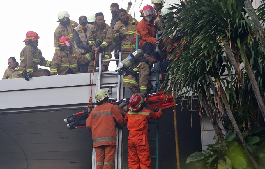 Sejumlah petugas pemadam kebakaran mengevakuasi korban yang terjebak, saat terjadi kebakaran di lantai 2 Gedung Cyber, Kuningan, Jakarta Selatan, Kamis, 2 Desember 2021.
