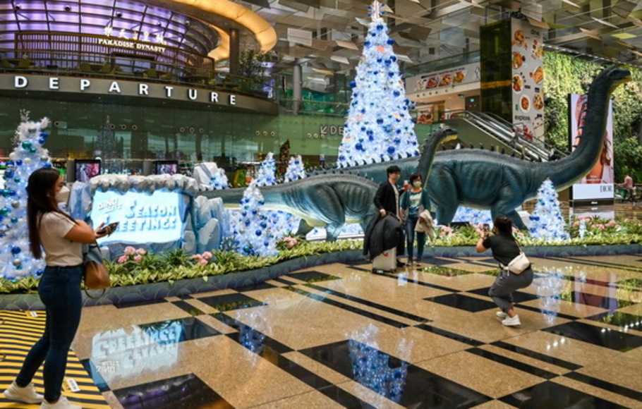 Orang-orang berpose dengan dekorasi Natal di aula keberangkatan di Bandara Internasional Changi di Singapura pada Kamis 2 Desember 2021. 