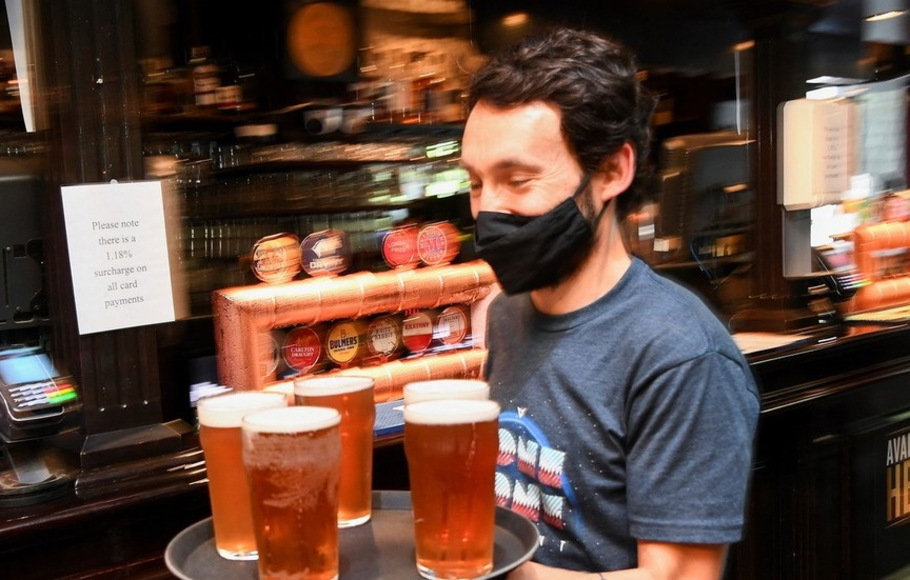 Seorang pelanggan membawa nampan bir ke mejanya di satu pub pusat kota Melbourne, Australia 22 Oktober 2021. 