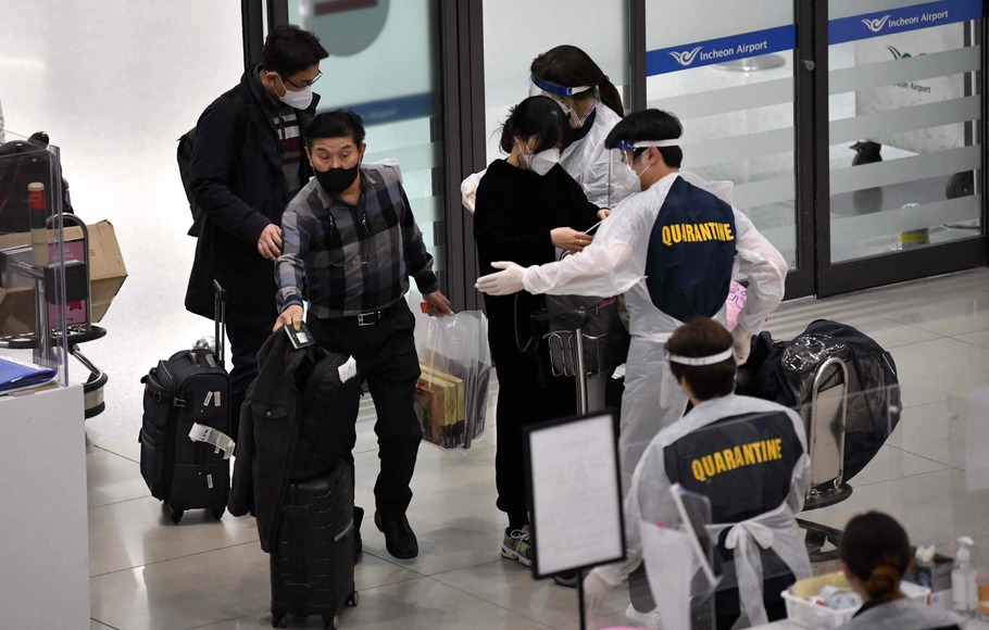 Petugas mengenakan APD memandu penumpang pesawat di aula kedatangan Bandara Internasional Incheon, Korsel, pada 30 November 2021, di tengah meningkatnya kekhawatiran tentang varian Omicron Covid-19.