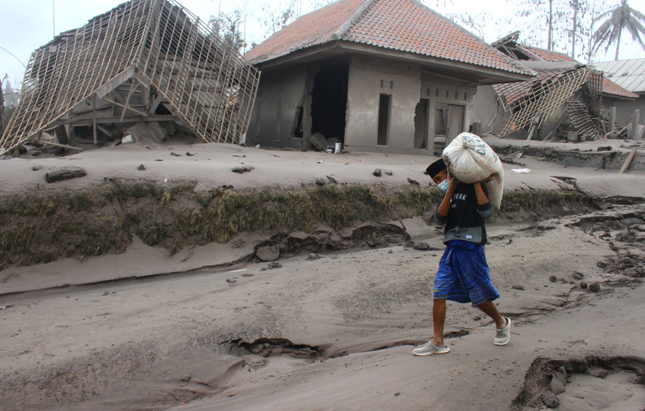 Seorang warga mengangkut barang yang bisa diselamatkan dari rumahnya yang hancur akibat erupsi gunung Semeru di desa Supiturang, Lumajang, Jawa Timur, Minggu, 5 Desember 2021.