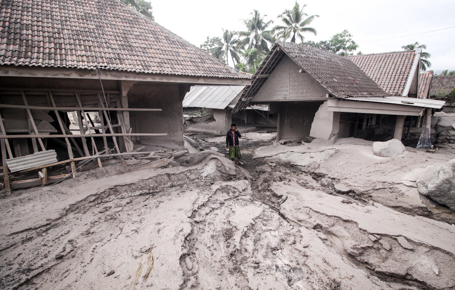 Warga melintas di rumah yang rusak akibat abu vulkanik letusan Gunung Semeru di Desa Sumber Wuluh, Lumajang, Jawa Timur, Minggu, 5 Desember 2021.
