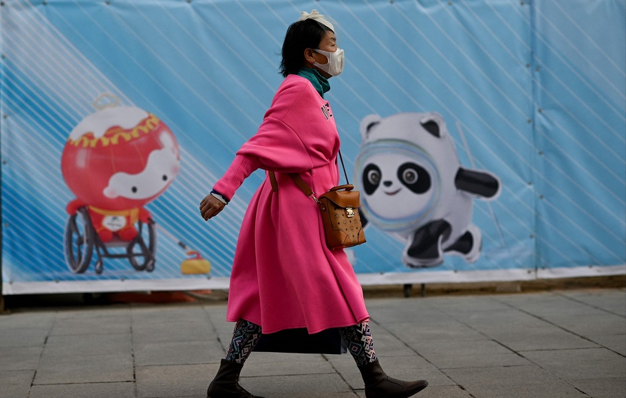 Seorang wanita berjalan melewati poster yang menunjukkan maskot Olimpiade dan Paralimpiade Musim Dingin Beijing 2022 di Beijing pada 5 Desember 2021. 