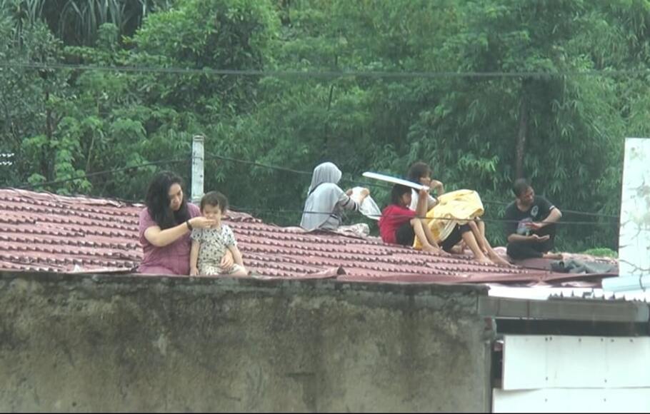 Korban banjir di wilayah Gunung Sari, Lombok Barat, Nusa Tenggara Barat, dievakuasi sementara di atas atap rumah mereka, Senin, 6 Desember 2021.