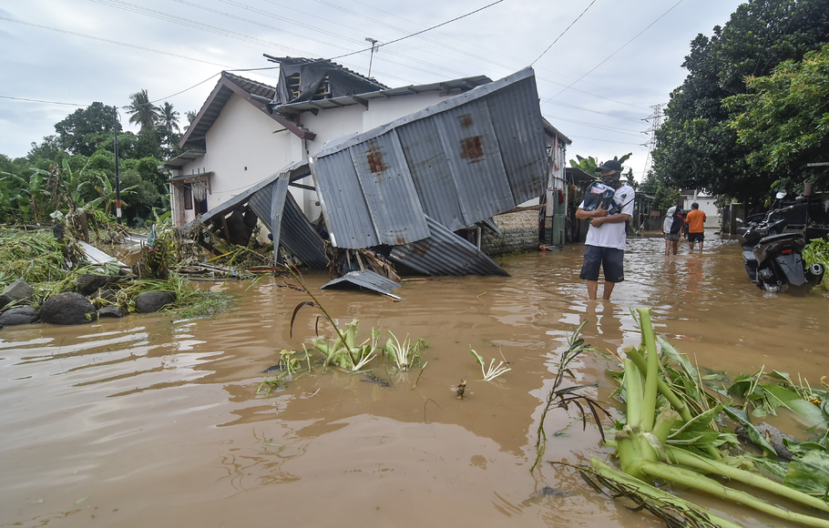 Warga melintas dekat bangunan yang roboh diterjang banjir di Perumahan Pondok Indah, Desa Jatisela, Kecamatan Gunungsari, Lombok Barat, NTB, Senin, 6 Desember 2021.