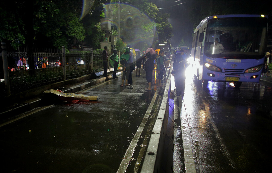 Sejumlah warga dan pengguna jalan menunggu mobil ambulance untuk evakuasi korban yang menjadi korban kecelakaan tertabrak bus Transjakarta di kawasan Jalan Margasatwa, Pasar Minggu, Jakarta Selatan, Senin 6 Desember 2021 malam. 