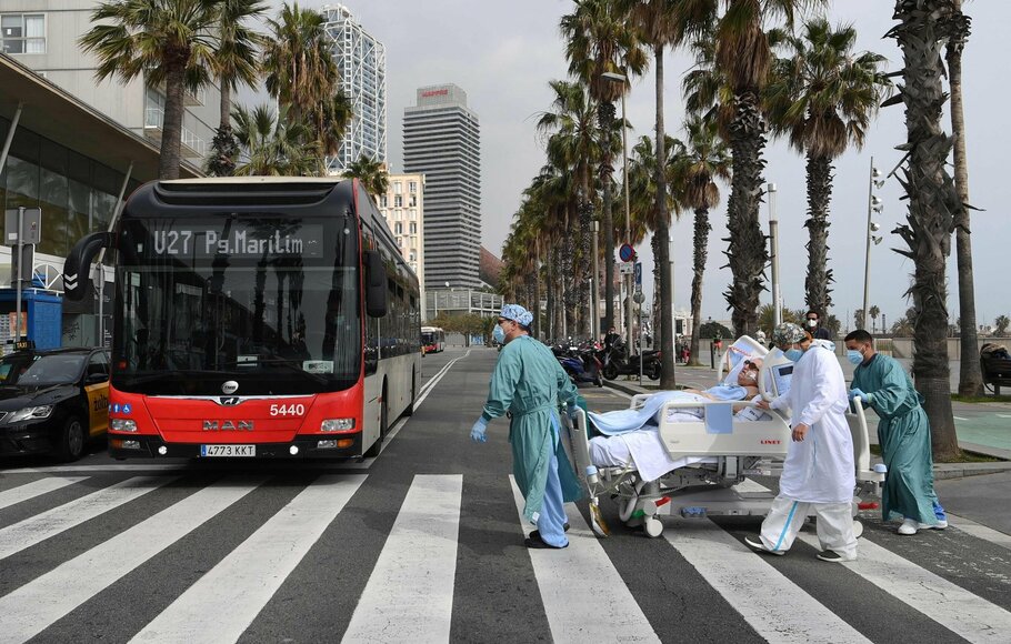 Petugas medis satu rumah sakit membawa pasien Covid-19 kembali ke rumah sakit setelah menghirup udara segar di tepi laut, di lapangan terbuka pantai Barceloneta di Barcelona, Spanyol, 4 Maret 2021. 