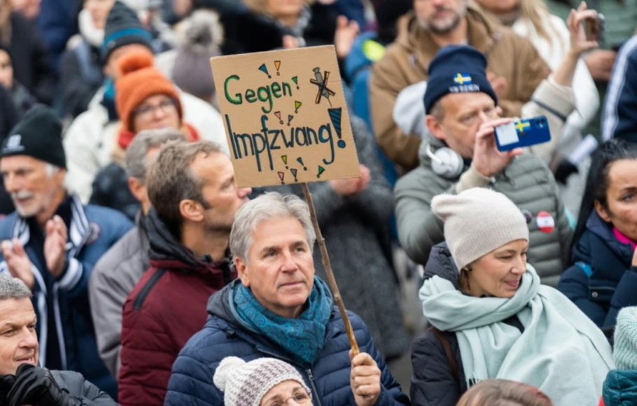 Seorang pengunjuk rasa memegang plakat bertuliskan 'Melawan vaksinasi wajib' selama rapat umum di Wina, Austria.