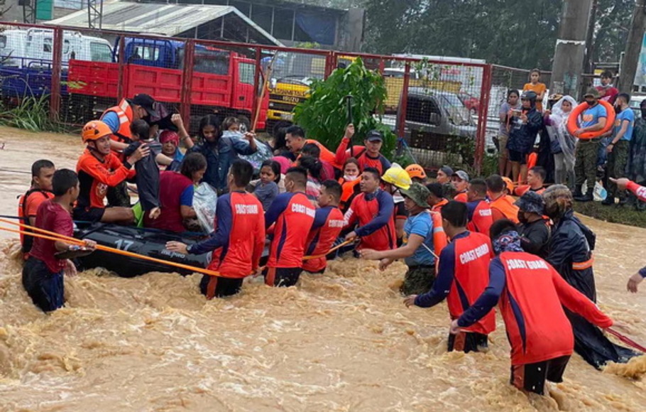 Para petugas penyelamat mengevakuasi penduduk dari rumah mereka yang terendam banjir di tengah hujan lebat yang dibawa oleh Topan Super Rai di Kota Cagayan de Oro, di pulau selatan Mindanao pada Kamis 16 Desember 2021.