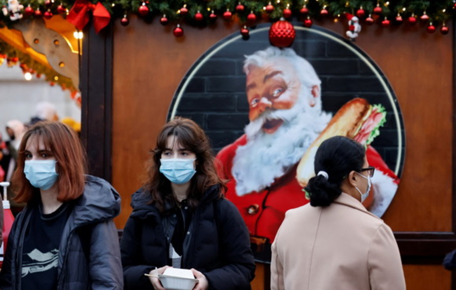 Pembeli, beberapa mengenakan masker wajah untuk memerangi penyebaran Covid-19, berjalan melewati kios-kios di pasar Natal di pusat kota London, Inggris pada Sabtu 18 Desember 2021. 