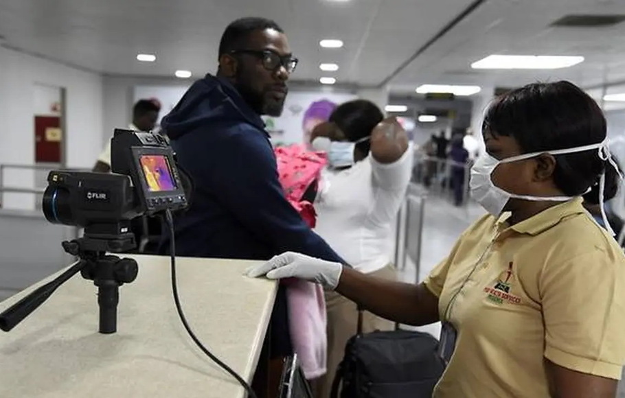Anggota staf Layanan Kesehatan Port berdiri di sebelah pemindai termal saat penumpang tiba di Bandara Internasional Murtala Mohammed di Lagos, Nigeria, pada 27 Januari 2019. 