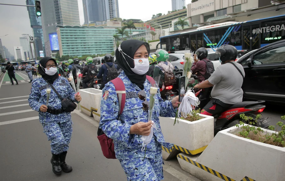 Sejumlah anggota kader Bela Negara membagikan bunga dan masker kepada pengguna jalan perempuan sebagai bentuk apresiasi dalam peringatan hari Ibu di Jalan MH Thamrin, Jakarta Pusat, Rabu, 22 Desember 2021. 