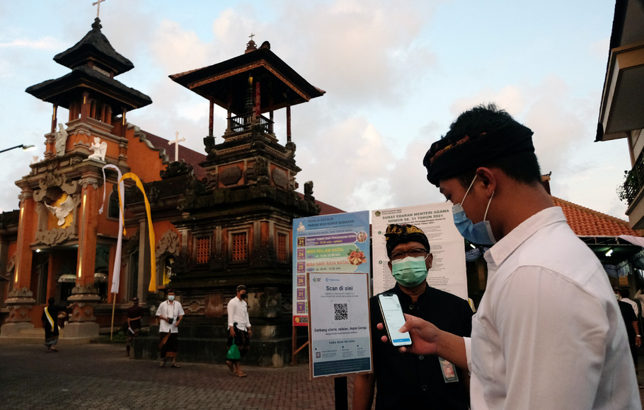 Umat Katolik memindai kode batang melalui aplikasi PeduliLindungi jelang mengikuti Misa Malam Natal di Gereja Katolik Paroki Roh Kudus Babakan, Desa Canggu, Badung, Bali, Jumat, 24 Desember 2021. 