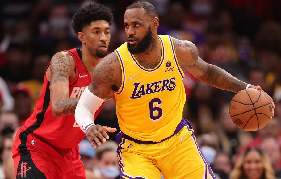 Pemain LA Lakers LeBron James membawa bola di depan pemain Houston Rockets Christian Wood pada pertandingan basket NBA, di Toyota Center, Houston.