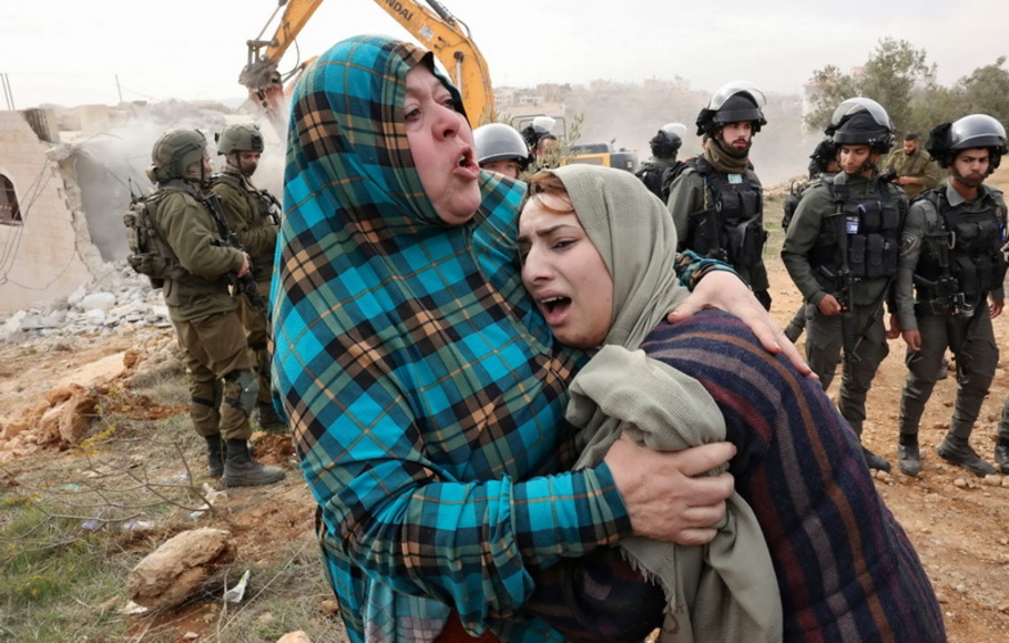 Pasukan Israel berjaga-jaga ketika para wanita Palestina bereaksi terhadap pembongkaran rumah mereka, yang terletak di dalam 