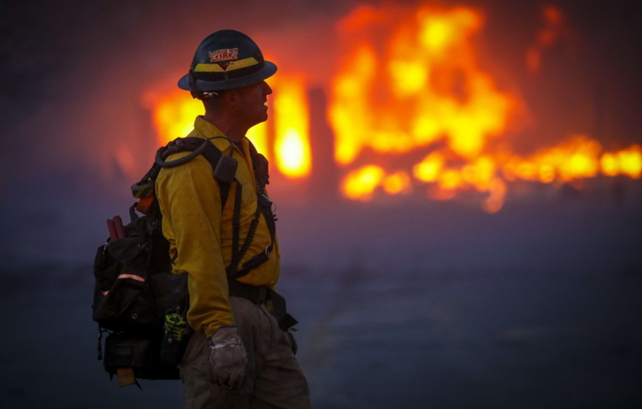 Seorang petugas pemadam kebakaran hutan belantara Mountain View berjalan melewati asap dan kabut setelah kebakaran hutan yang bergerak cepat menyapu area di lingkungan Centennial Heights di Louisville, Colorado, AS pada Kamis 30 Desember 2021.