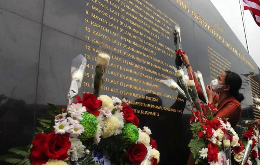Salah seorang keluarga awak kapal selam KRI Nanggala-402 menempelkan bunga di dinding yang terpampang nama prajurit gugur di lingkungan Markas Koarmada II Surabaya, Sabtu 15 Januari 2022.