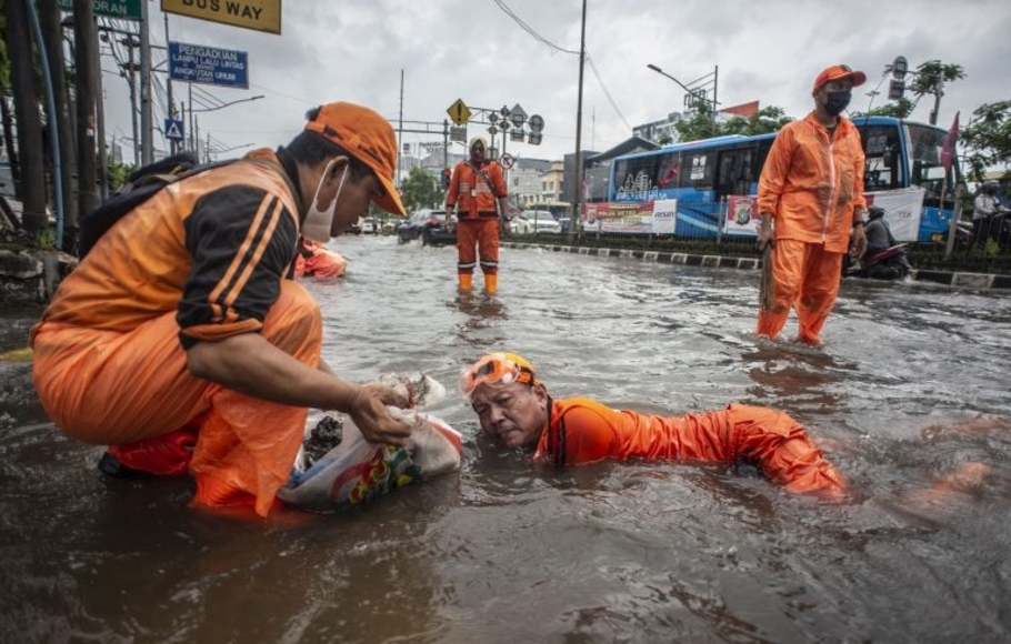 Petugas PPSU membersihkan sampah yang menyumbat saluran air saat banjir di Jalan Gunung Sahari, Mangga Dua, Jakarta, Selasa 18 Januari 2022. 