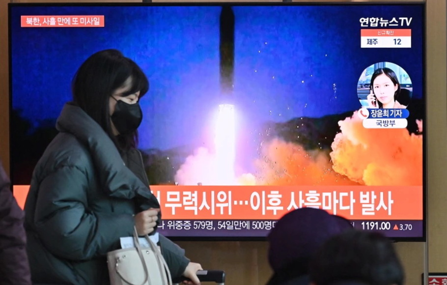 Seorang wanita berjalan melewati layar televisi yang menunjukkan siaran berita dengan rekaman file uji coba rudal Korea Utara, di satu stasiun kereta api di Seoul pada Kamis 20 Januari 2022.