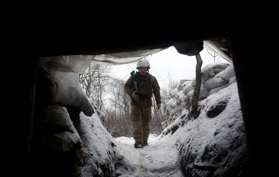 Seorang prajurit militer Ukraina berjalan di sepanjang parit yang tertutup salju di garis depan dengan wilayah separatis yang didukung Rusia di dekat desa Zolote, di wilayah Lugansk timur, pada 21 Januari 2022.
