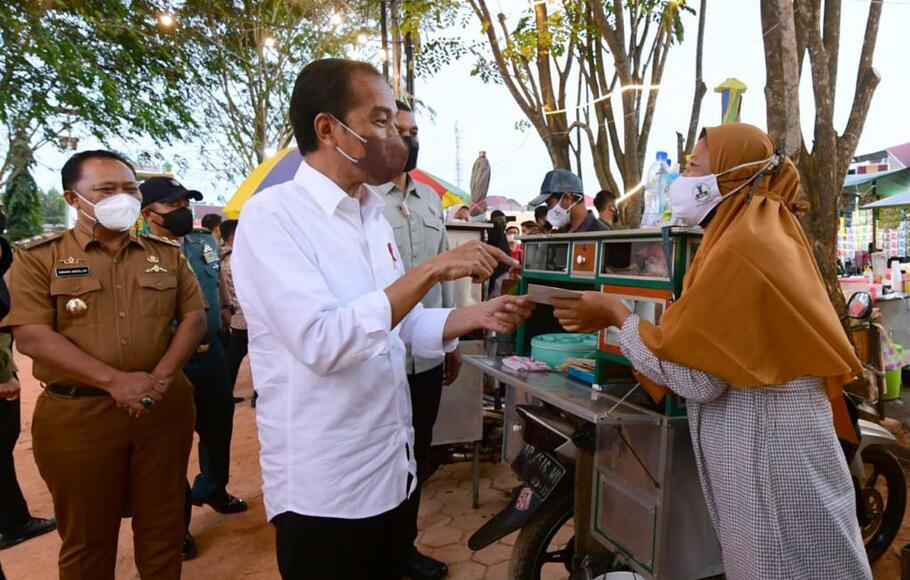 Presiden Joko Widodo menyerahkan bantuan tunai bagi para pedagang di Taman Batu 10 Kawasan Pasar Bintan Center, Kota Tanjung Pinang, Selasa, 25 Januari 2022
