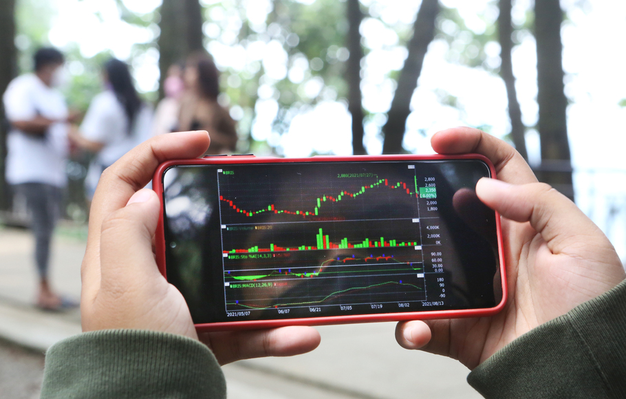Investor memantau pergerakan saham mengunakan ponsel.