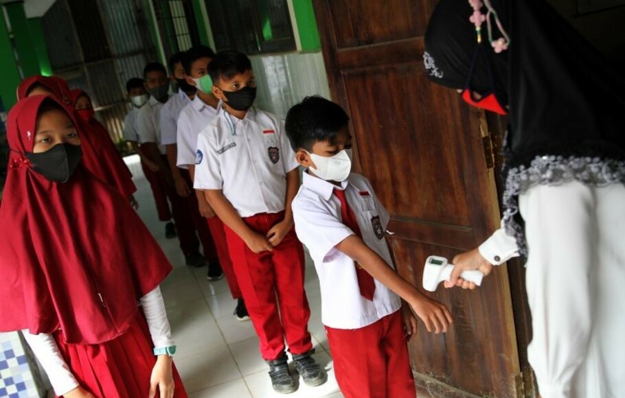 Seorang guru mengecek suhu tubuh siswa sebelum masuk ke ruang kelas di SD Negeri 10 Kendari, Kendari, Sulawesi Tenggara, Rabu, 8 September 2021. 