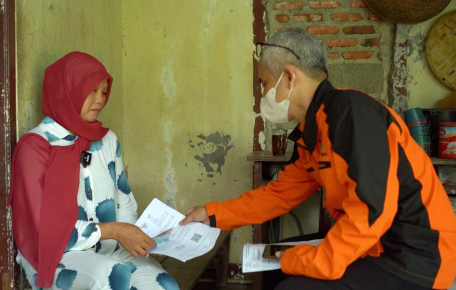 Petugas  Pos Indonesia sedang menyalurkan bantuan dana sembako kepada warga. 
