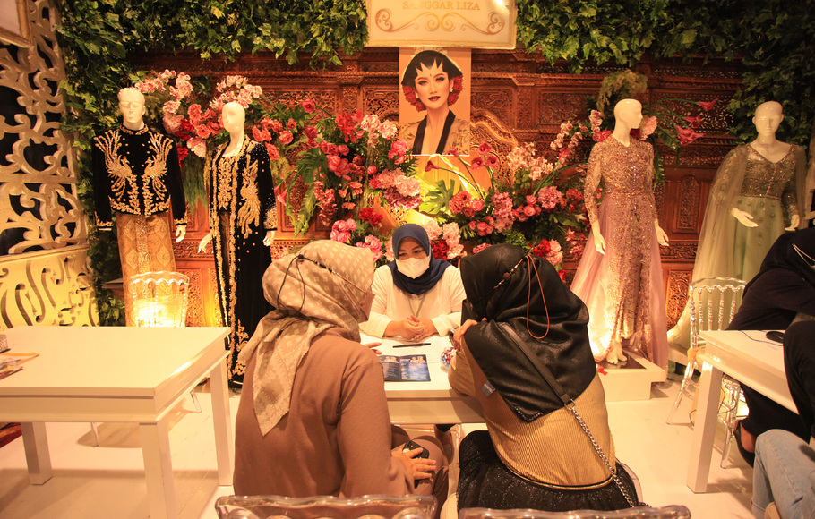 Pengunjung berbincang di stan busana pernikahan dalam pameran Pernikahan Nasional dan Tradisional di Lagoon Garden , Hotel Sultan, Jakarta, Minggu, 6 Maret 2022.