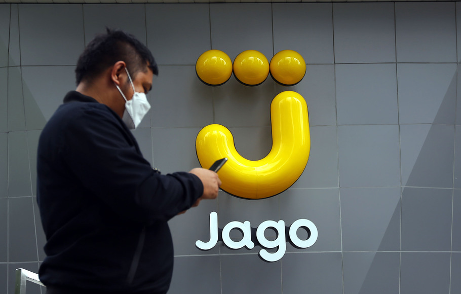 Karyawan melintas di depan logo Bank Jago di Jakarta.