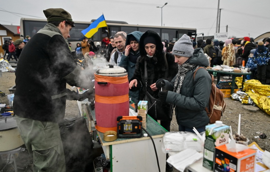 Para pengungsi mendapatkan minuman panas saat mereka menunggu dalam suhu dingin yang membekukan untuk naik bus, setelah melintasi perbatasan Ukraina ke Polandia, di perbatasan Medyka di Polandia, pada Senin 7 Maret 2022.
