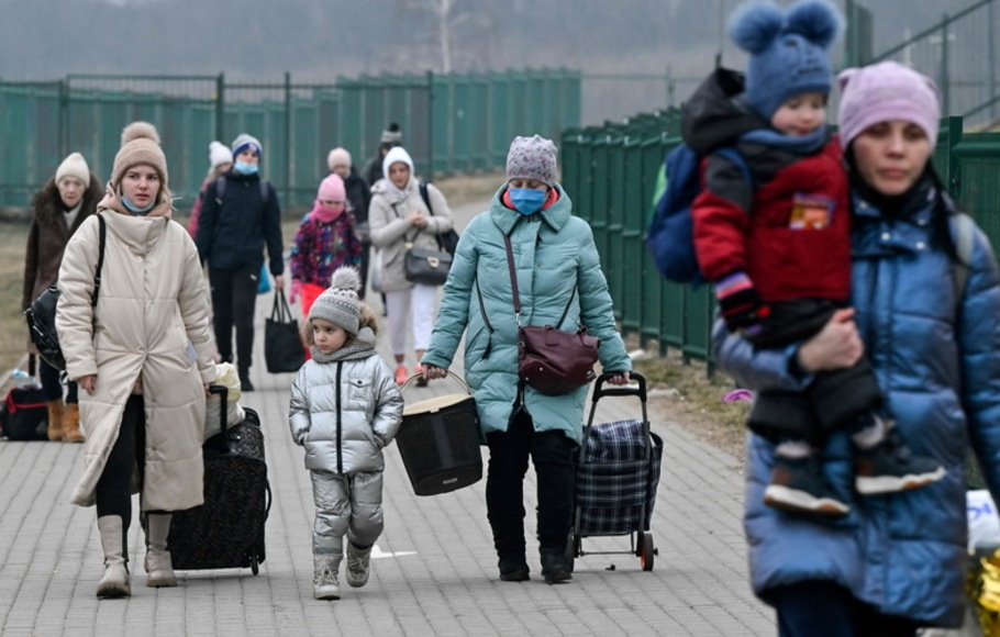 Wanita dengan anak-anak mereka melintasi perbatasan Ukraina ke Polandia, di perbatasan Medyka pada Selasa 8 Maret 2022. 