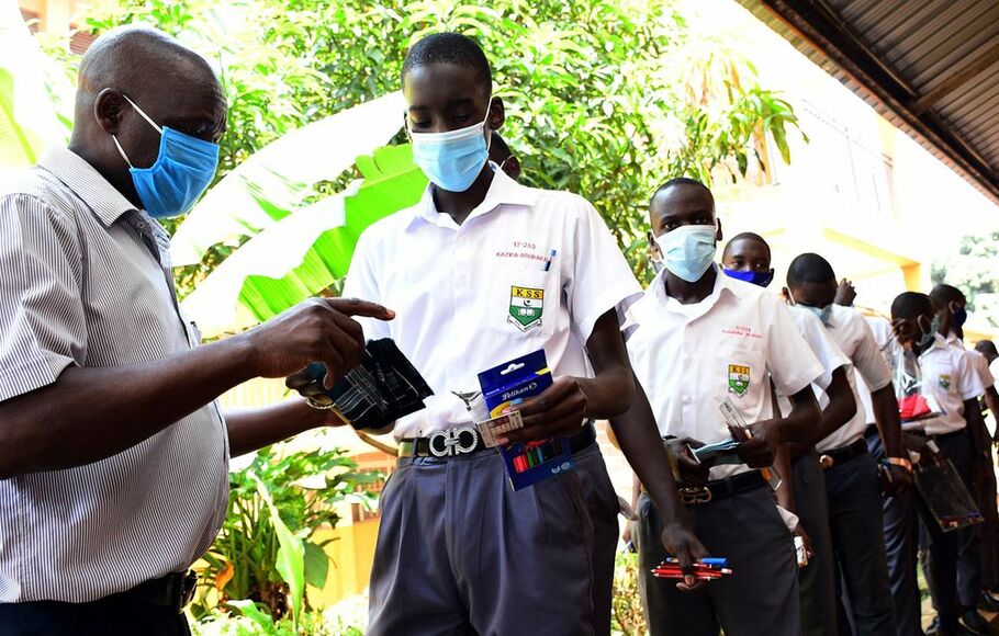 Pengawas memeriksa siswa di Sekolah Menengah Kibuli di Kampala, Uganda sebelum ujian mereka pada 1 Maret 2021. Siswa Uganda kembali ke sekolah pada 10 Januari 2022, setelah dihentikan karena pandemi Covid-19.