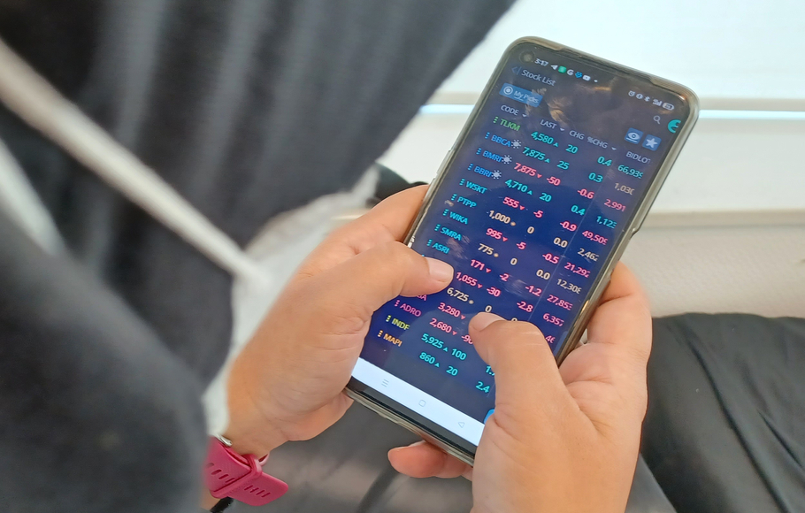 Investor melihat indeks saham di ponselnya di Jakarta.