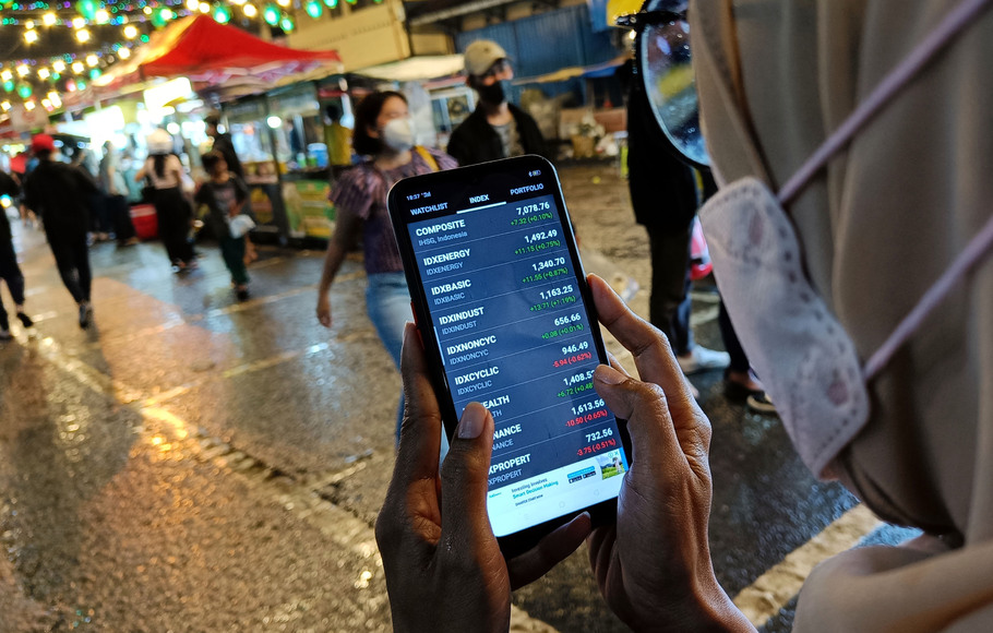 Seorang investor melihat pergerakan saham melalui smartphone, di Tangerang, Banten.