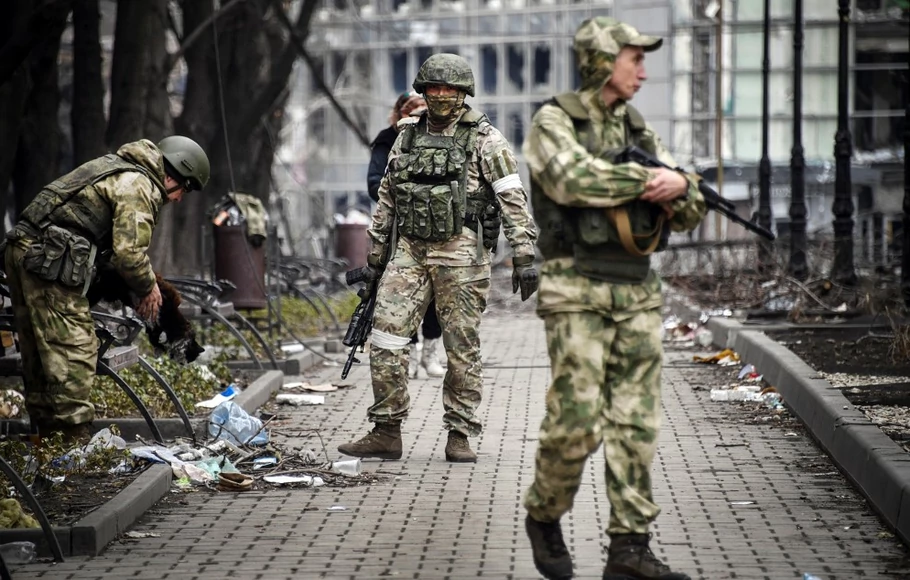 Tentara Rusia berjalan di sepanjang jalan di Mariupol pada 12 April 2022.