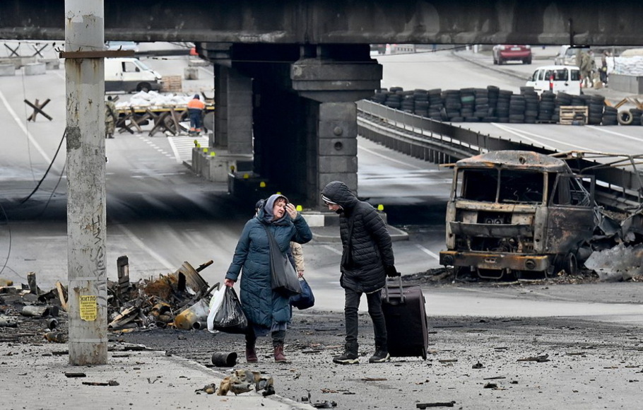 Orang-orang membawa barang-barang mereka saat mereka berjalan melewati puing-puing pertempuran pekan lalu di ibu kota Ukraina, Kyiv pada 4 Maret 2022.