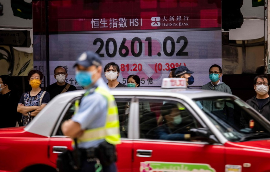 Orang-orang berjalan melewati pajangan yang menunjukkan Indeks Hang Seng di Hong Kong pada Jumat 22 April 2022. 