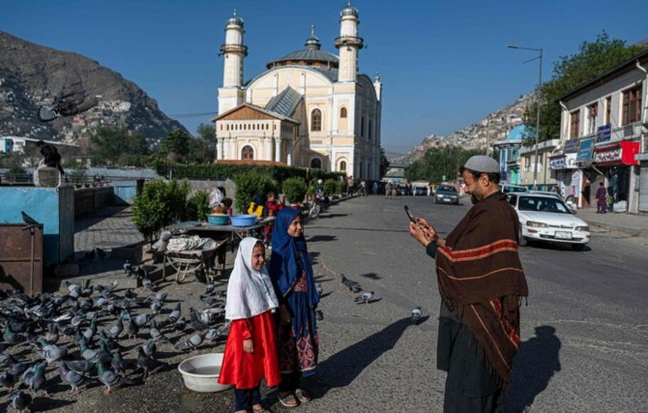 Seorang bapak mengambil foto dua anak perempuan di pinggir jalan, Afghanistan. Bagi jutaan orang Afghanistan, Idulfitri adalah hari lain perjuangan untuk menyediakan makanan ke atas meja.