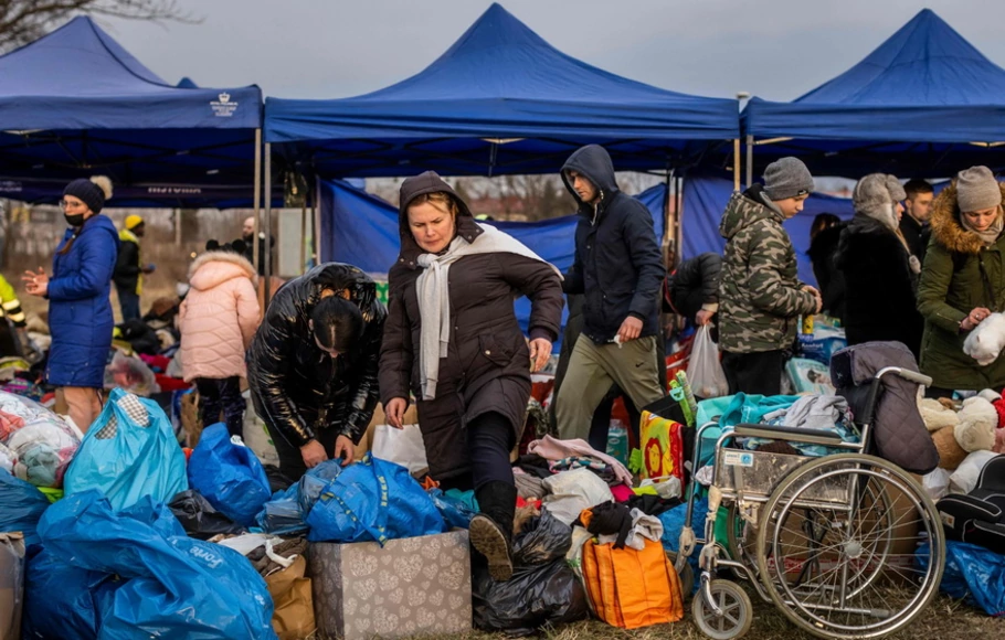 Para relawan memberikan bantuan bagi pengungsi Ukraina saat mereka tiba dengan bus dari penyeberangan perbatasan pejalan kaki Medyka, di Przemsyl, Polandia timur pada 26 Februari 2022, setelah invasi Rusia ke Ukraina.