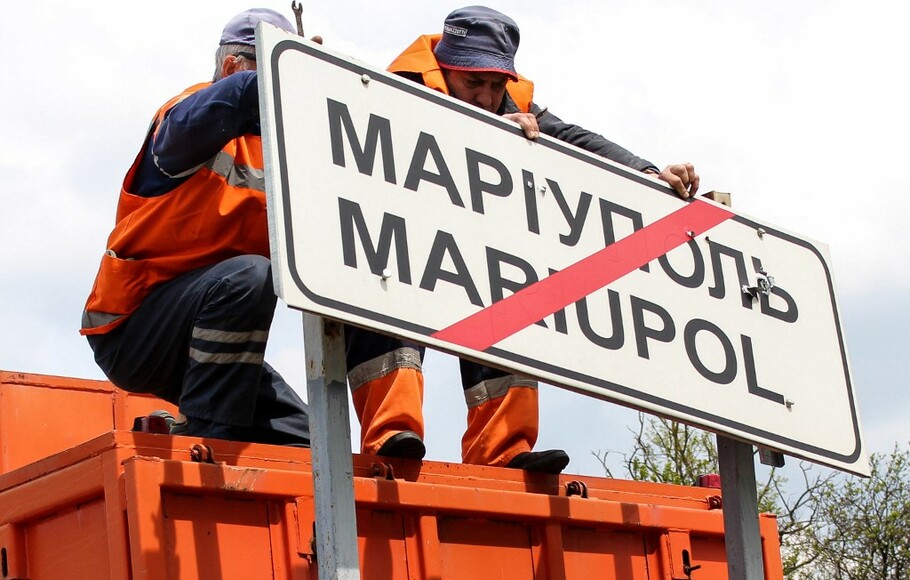 Foto dari Kementerian Transportasi Republik Rakyat Donetsk pada 5 Mei 2022 menunjukkan pekerja kota mengubah rambu jalan Ukraina menjadi Rusia di luar kota Mariupol.
