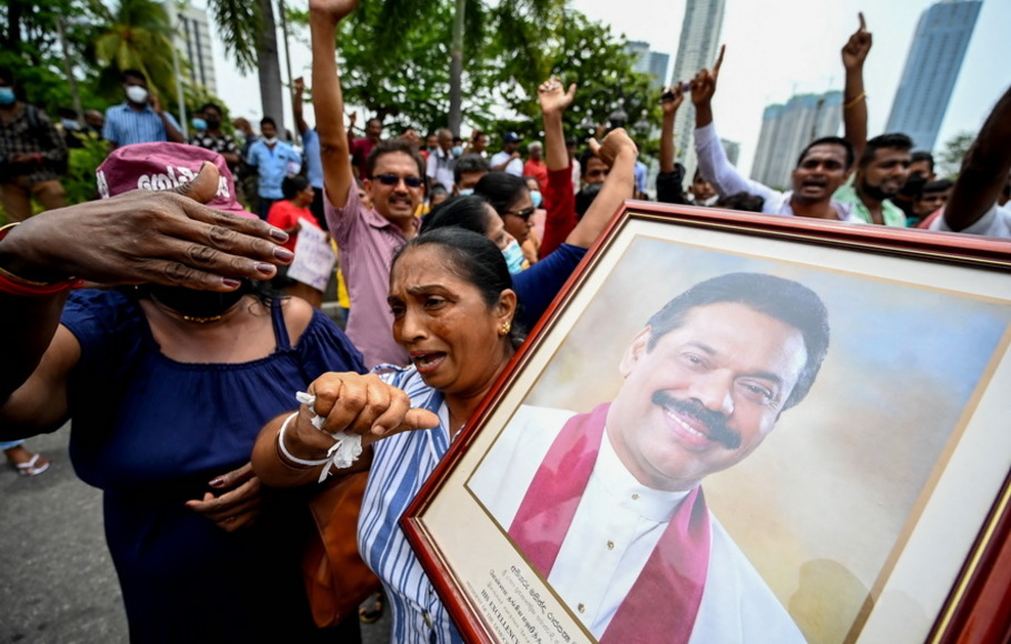 Pendukung pro-pemerintah memegang potret Perdana Menteri Mahinda Rajapaksa saat memprotes di luar kediaman perdana menteri di Kolombo pada Senin 9 Mei 2022. 