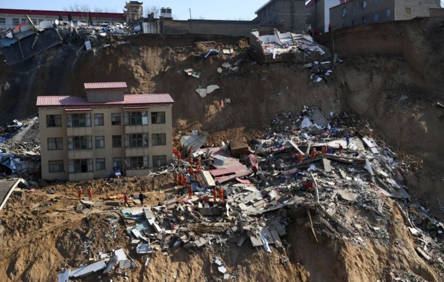 Petugas penyelamat berada di sekitar reruntuhan rumah yang roboh akibat longsor di Tiongkok.