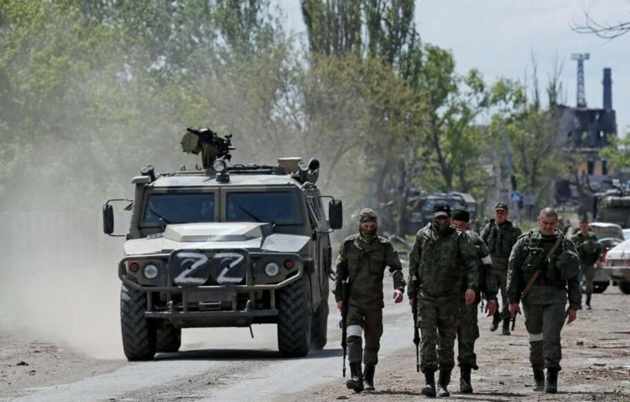 Anggota layanan pasukan pro-Rusia berjalan di sepanjang jalan di kota pelabuhan selatan Mariupol, Ukraina, 17 Mei 2022.