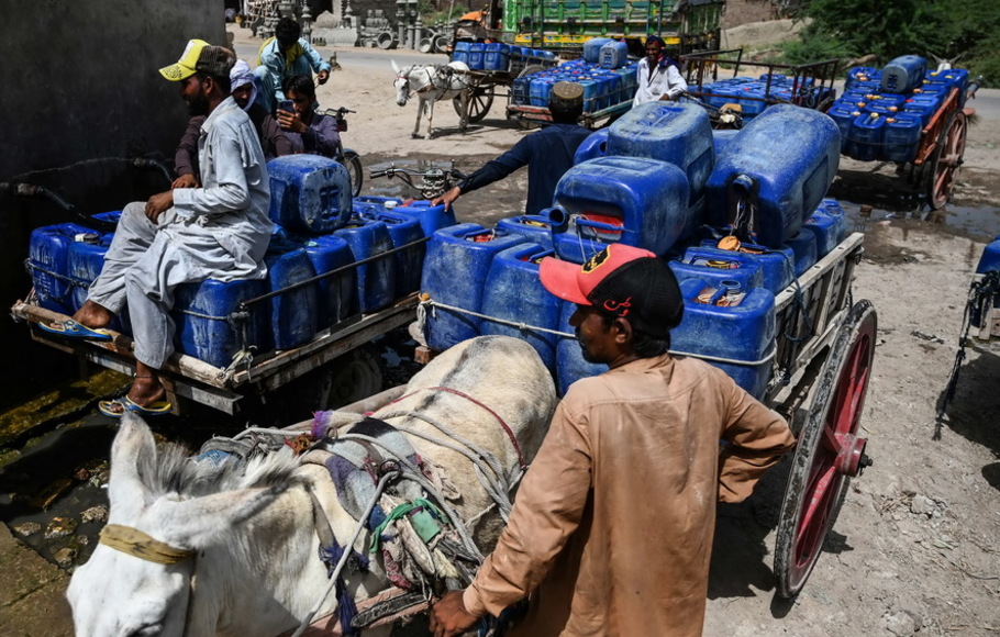 Para penjual mengisi kaleng dengan air minum dari pabrik penyedia air untuk dijual selama gelombang panas di kota terpanas di Pakistan, Jacobabad, di provinsi Sindh selatan pada Rabu 11 Mei 2022.