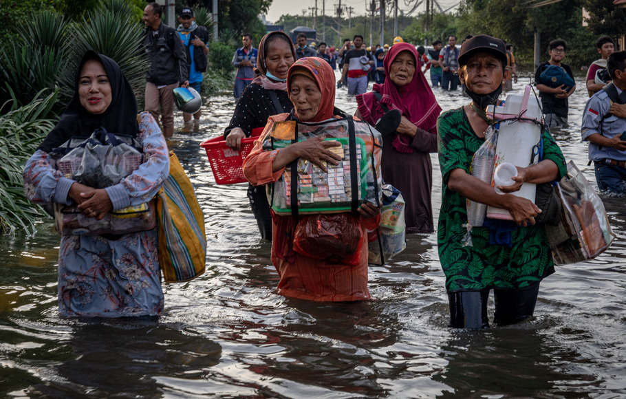 Sejumlah pedagang asongan pelabuhan berjalan menembus banjir limpasan air laut ke daratan atau rob yang merendam kawasan Pelabuhan Tanjung Emas Semarang, Jawa Tengah, Senin 23 Mei 2022.