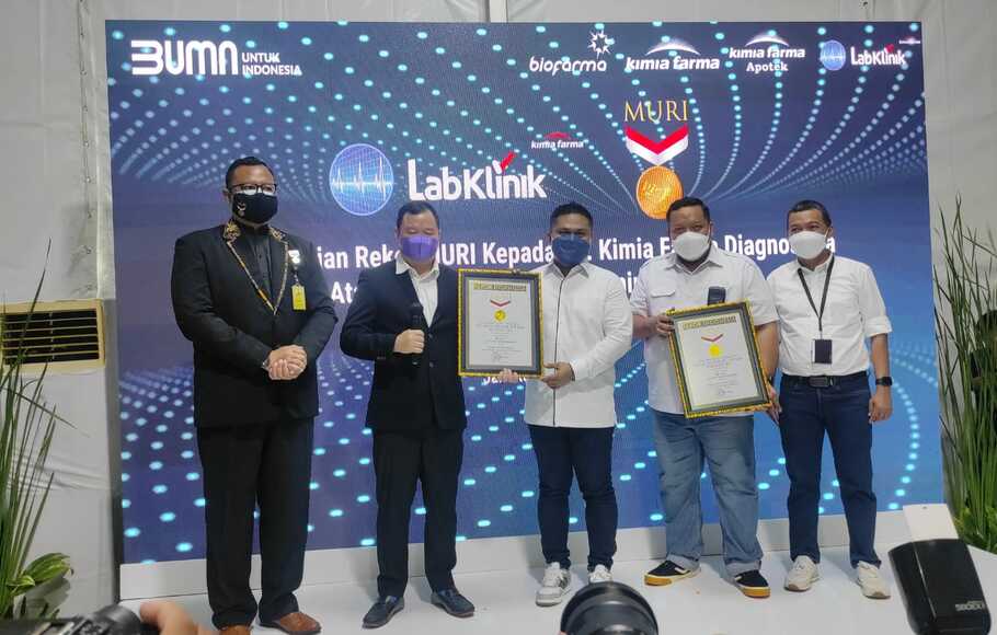 Direktur Utama Kimia Farma Diagnostika, Ardhy Nugrahanto Wokas (tengah) bersama dengan direksi KFD berfoto bersama dengan perwakilan Muri yang menyerahkan rekor Muri dengan menerima dua penghargaan sekaligus.